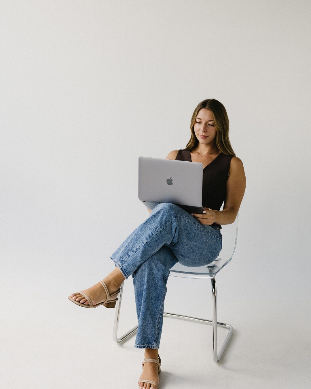 girl sitting in a clear chair with her laptop
